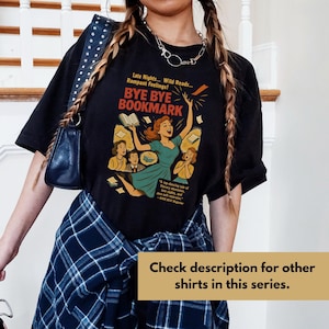 May include: Black t-shirt with a retro graphic that says "BYE BYE BOOKMARK." The design shows a woman in a teal dress, surrounded by books, with text that reads "Late Nights... Wild Reads... Rampant Feelings!" and "A top-dancing tale of literary obsession."
