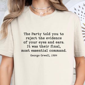 Könnte beinhalten: Ein weißes T-Shirt mit einem schwarzen Zitat aus George Orwells 1984: "The Party told you to reject the evidence of your eyes and ears. It was their final, most essential command. George Orwell, 1984"
