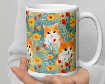 May include: White ceramic mug with a colorful design of orange and white kittens in a field of yellow and red flowers.
