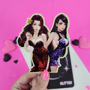 May include: Two women in glamorous dresses, one in red and one in blue, are depicted in a sticker. The sticker has a gold outline and is set against a pink background.