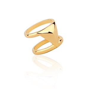 May include: A gold ring with a triangular design. The ring is double-banded and has a geometric shape.