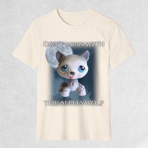May include: A beige t-shirt with a cartoon wolf in front of a moon. The text "Don't mess with the alpha wolf" is printed on the shirt.