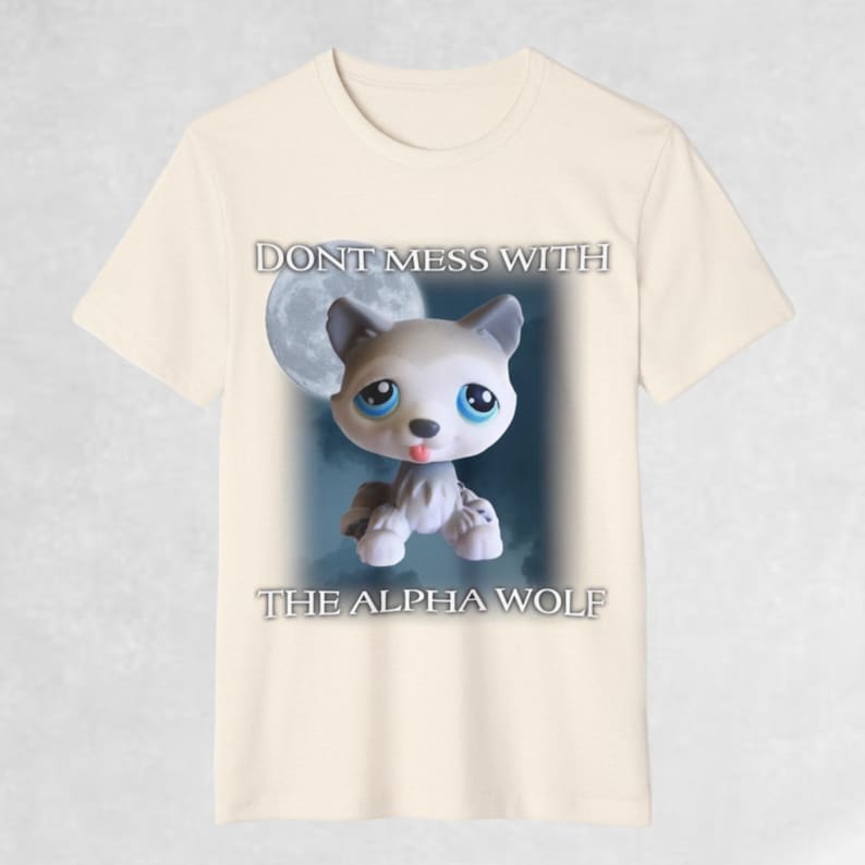 May include: A beige t-shirt with a cartoon wolf in front of a moon. The text "Don't mess with the alpha wolf" is printed on the shirt.