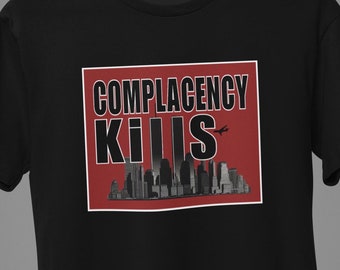 May include: Black t-shirt with a red rectangle graphic that says "COMPLACENCY KILLS" in white text with a black silhouette of a city skyline and a plane in the background.