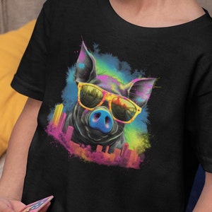 May include: A black t-shirt with a colorful graphic of a pig wearing sunglasses. The pig is surrounded by a colorful watercolor-like background with a cityscape in the background.