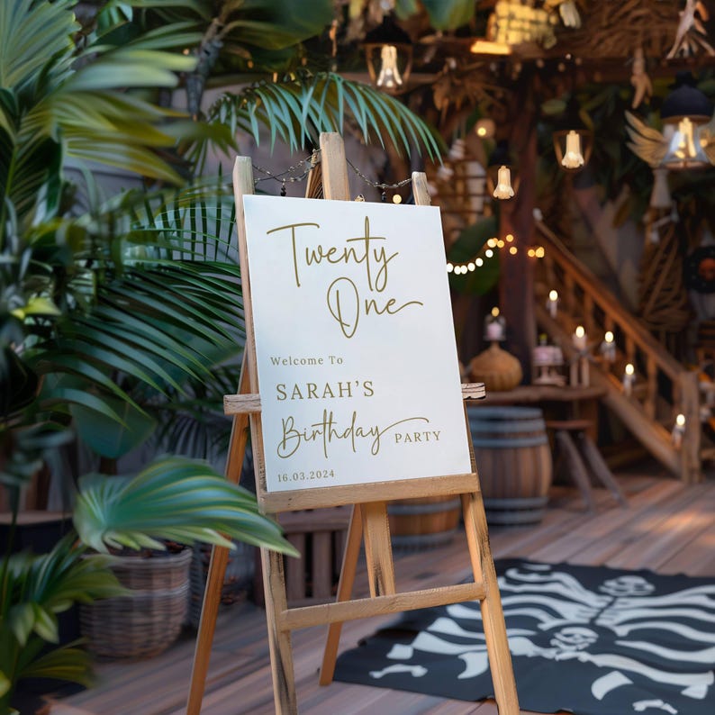 May include: White sign with gold lettering on an easel. The sign reads "Twenty One" and "Welcome to Sarah's Birthday Party 16.03.2024".