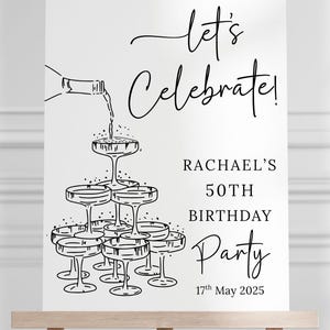 Puede incluir: Un letrero rectangular blanco con un dibujo de l&iacute;neas negras de una torre de copas de champ&aacute;n siendo llenada por una botella. El texto dice: let's celebrate! RACHAEL'S 50TH BIRTHDAY Party 17th May 2025. El letrero est&aacute; sobre un caballete de madera.