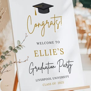 Puede incluir: Un letrero de fiesta de graduaci&oacute;n sobre un caballete de madera. El letrero dice "&iexcl;Felicidades!" en escritura dorada, seguido de "Bienvenida a la fiesta de graduaci&oacute;n de Ellie" y detalles sobre la Universidad de Liverpool, Clase de 2025. Incluye una ilustraci&oacute;n de un birrete negro.