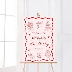 May include: A pink sign on a wooden easel, featuring red line art illustrations. The sign reads "Welcome to Olivia's Hen Party" with drawings of a bouquet, bow, champagne glasses, hearts, shoes, a ring, and a cake. The date 27.07.2025 is also shown.