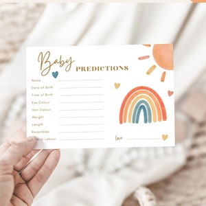 May include: A baby shower activity card with the words "Baby Shower Activity" at the top. The card features a rainbow and sun graphic, with spaces for predictions like name, date of birth, and weight. The card is held by a hand.