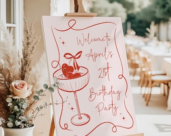 May include: A rectangular sign on a wooden easel featuring a light pink background with red line art. The design includes a cocktail glass with cherries and a bow, surrounded by a decorative border and the text Welcome to April's 21st Birthday Party.