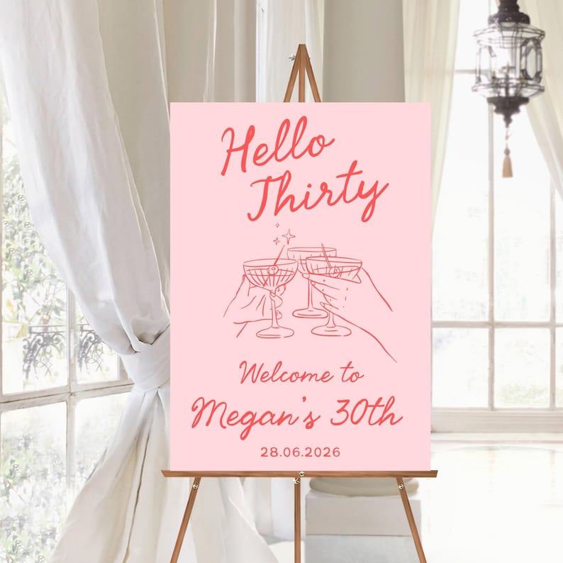 May include: A rectangular pink sign featuring red text that reads Hello Thirty, Welcome to Megan's 30th, and 28.06.2026. The center graphic displays line art of three hands holding cocktail glasses with olives, all rendered in a matching red tone.