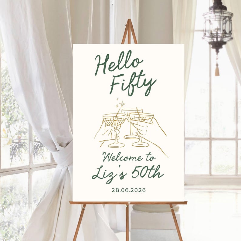 May include: A white rectangular welcome sign featuring dark green text that reads Hello Fifty, Welcome to Liz's 50th, and the date 28.06.2026. The center displays a gold line art illustration of two hands holding martini glasses with a small star.