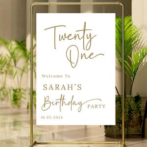 May include: White sign with gold text that reads "Twenty One" and "Welcome to Sarah's Birthday Party" with the date "16.03.2024".