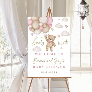 K&ouml;nnte beinhalten: Ein rosa-braunes Willkommens-Schild f&uuml;r eine Babyparty mit einem Teddyb&auml;ren, der Ballons h&auml;lt. Auf dem Schild steht "We can Bearly Wait! Welcome to Emma and Jay's Baby Shower 02.11.2024"