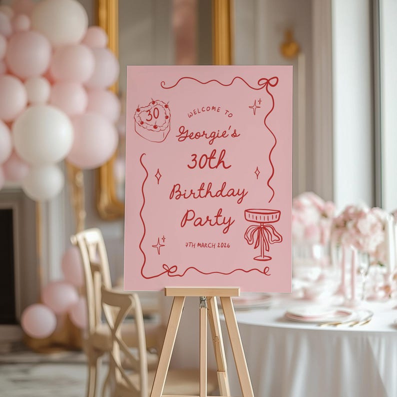 K&ouml;nnte beinhalten: Ein rosa Schild auf einer Holzstaffelei mit roter Schrift, das "Georgies 30. Geburtstagsparty" ank&uuml;ndigt. Der Text enth&auml;lt Illustrationen von Kuchen und Tisch. Der Hintergrund zeigt rosa und wei&szlig;e Ballons.