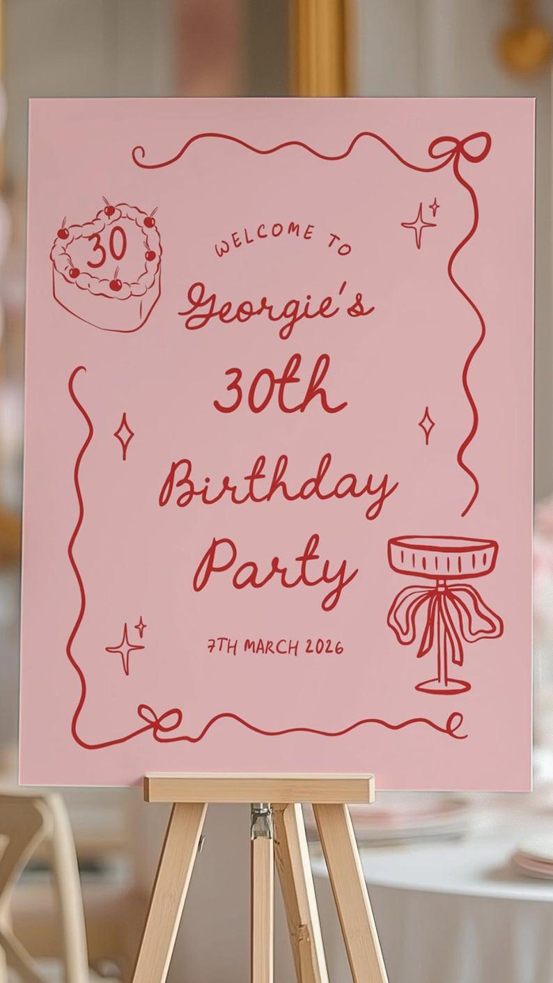 K&ouml;nnte beinhalten: Ein rosa Schild auf einer Staffelei mit roten Illustrationen und Text. Auf dem Schild steht "Willkommen zu Georgies 30. Geburtstagsparty, 7. M&auml;rz 2026." Illustrationen umfassen einen herzf&ouml;rmigen Kuchen und einen dekorativen Tisch.