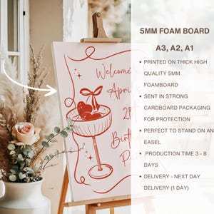 May include: A 5mm foam board sign featuring red line art of a cocktail glass with cherries and the text Welcome to April's 21st Birthday Party. The board is displayed on a wooden easel next to a vase with dried flowers and a pink rose.