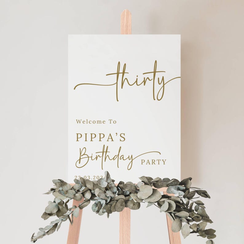 May include: A white sign on a wooden easel with gold lettering that reads "thirty", "Welcome to Pippa's Birthday Party", and the date. A garland of green leaves adorns the bottom of the sign.