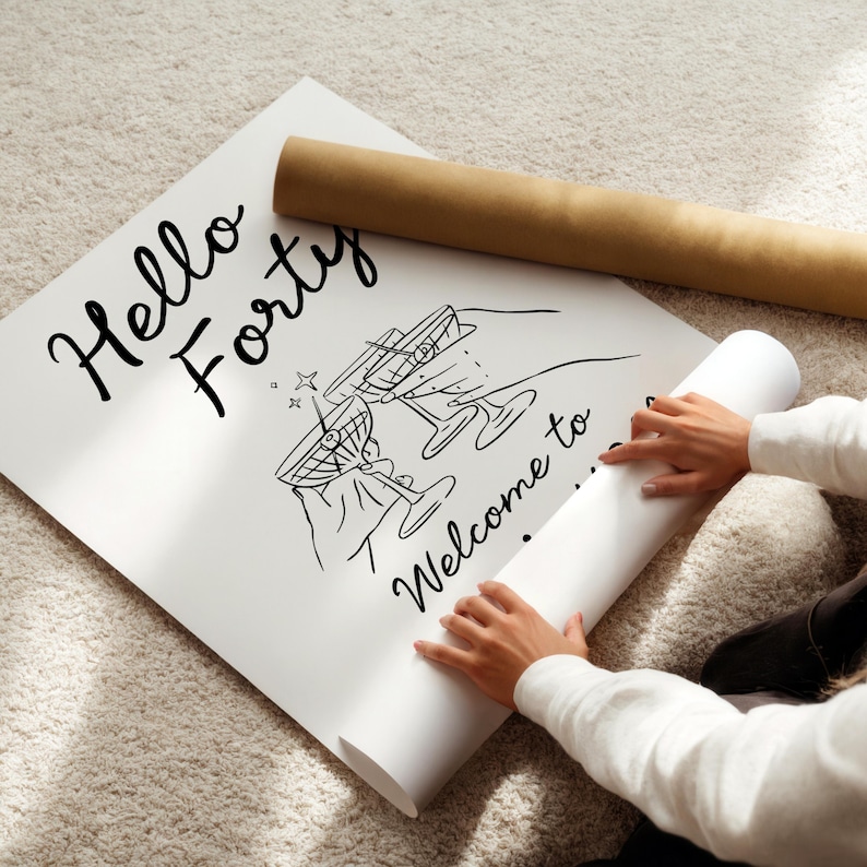 May include: A white poster featuring black line art of two hands holding martini glasses with olives. The text reads Hello Forty and Welcome to. The poster is partially rolled up, with a brown cardboard shipping tube resting on the top edge.