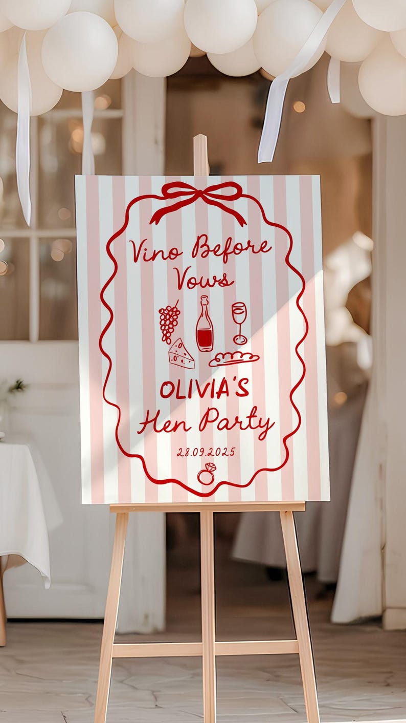 May include: A wooden easel displays a sign with a pink and white striped background. The sign features red text and illustrations, including the words "Vino Before Vows" and "Olivia's Hen Party". The date 28.09.2025 is also displayed.