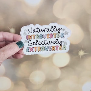 May include: White sticker with the text "Naturally Introverted, Selectively Extroverted" in colorful letters with small flower accents.