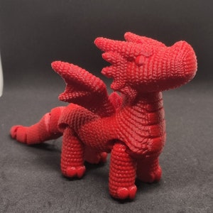 May include: A red articulated dragon toy with a textured surface. The dragon has wings, a tail, and four legs.