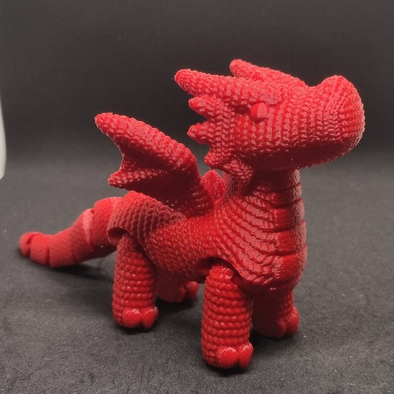 May include: A red articulated dragon toy with a textured surface. The dragon has wings, a tail, and four legs.