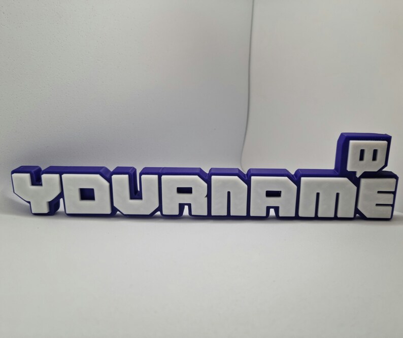 May include: A purple and white plastic nameplate with the text "YOURNAME" and a purple Twitch logo.