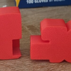 Puede incluir: Dos letras de espuma roja que deletrean la palabra "BOOM" en un estilo audaz y tridimensional.