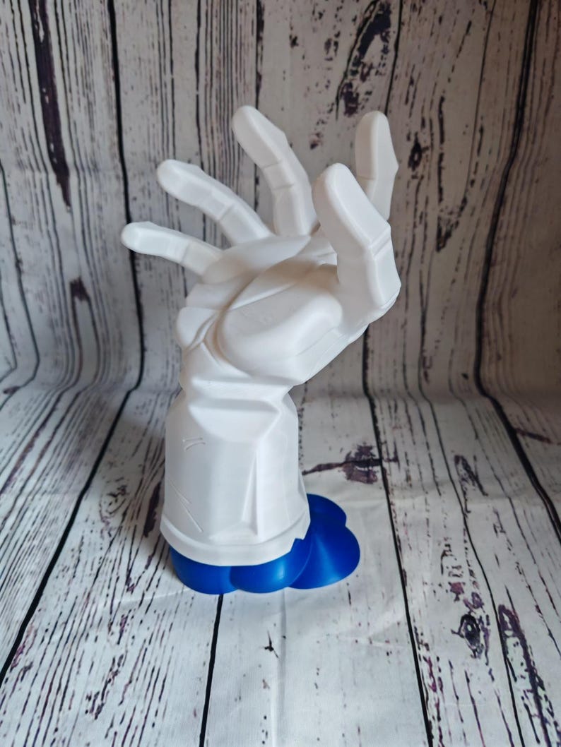 K&ouml;nnte beinhalten: Eine wei&szlig;e, 3D-gedruckte Handskulptur mit einem blauen Sockel. Die Hand ist mit ausgestreckten und leicht gekr&uuml;mmten Fingern positioniert. Die Skulptur ist ein einzigartiges und modernes Kunstwerk.