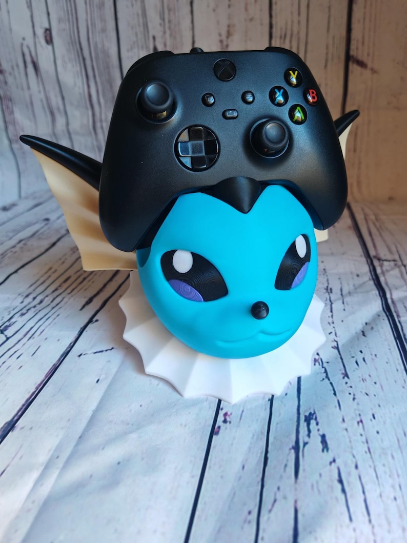 May include: A blue and white 3D printed Pokemon character holding a black Xbox controller.