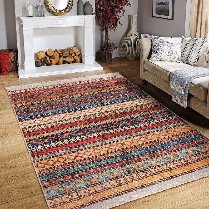 Hereke Motif Rug-A colorful, striped rug with a geometric pattern in shades of red, orange, blue, and yellow. The rug has a fringe border.