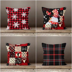 May include: Four decorative throw pillows with winter-themed designs. One pillow features a red and black buffalo plaid pattern with white snowflakes. Another has a snowman design. The third has a patchwork design with axes and deer. The last has a black and red plaid pattern.