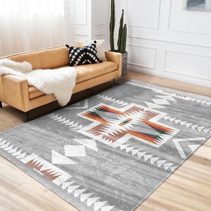 May include: A gray area rug with a white, brown, and multi-colored geometric pattern. The rug has a distressed look and is perfect for a living room or bedroom.