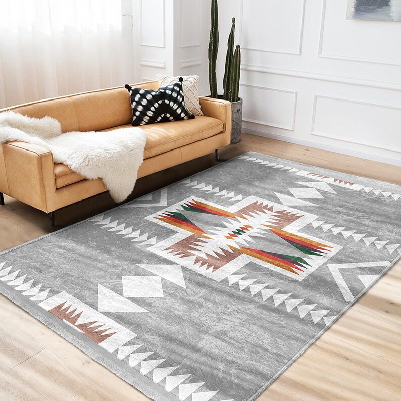 May include: A gray area rug with a white, brown, and multi-colored geometric pattern. The rug has a distressed look and is perfect for a living room or bedroom.