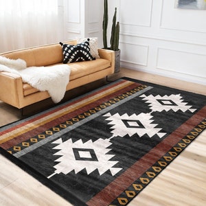 May include: Black and white geometric rug with red, gold, and brown stripes. The rug has a southwestern design with diamond shapes and a black background.