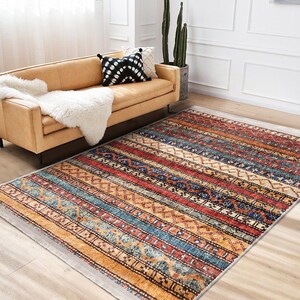 Hereke Motif Rug-A colorful, striped rug with a geometric pattern in shades of red, orange, blue, and yellow. The rug has a fringe border.