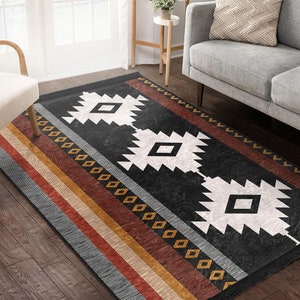 May include: A black and white geometric rug with a southwestern design. The rug has a fringed border and features a pattern of diamonds and triangles. The rug is on a wooden floor.