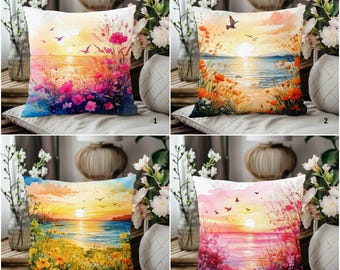 May include: Four decorative cushions with watercolour sunset scenes. Each cushion features a different sunset design with vibrant colours, including pink, orange, yellow, and blue. The designs include flowers, birds, and water.