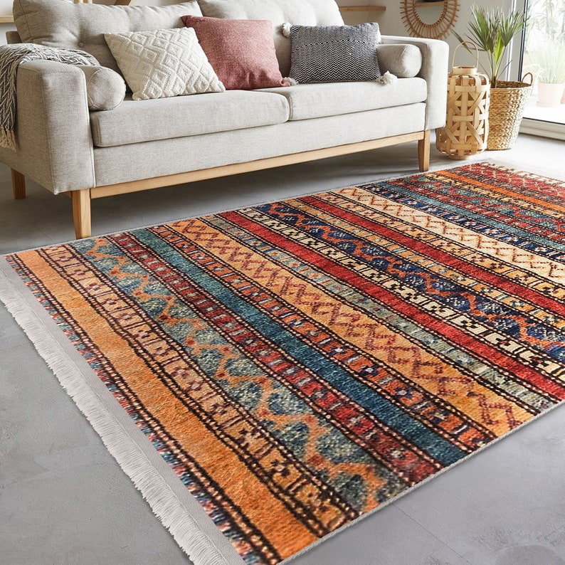 Hereke Motif Rug-A colorful, striped rug with a geometric pattern in shades of red, orange, blue, and yellow. The rug has a fringe border.