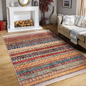 Hereke Motif Rug-A colorful, striped rug with a geometric pattern in shades of red, orange, blue, and yellow. The rug has a fringe border.