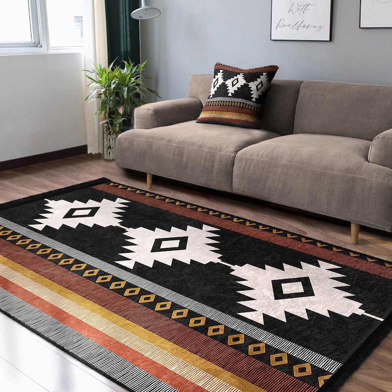 May include: Black and white geometric rug with a brown, orange and red striped border. The rug has a southwestern design with diamond shapes and a black background.