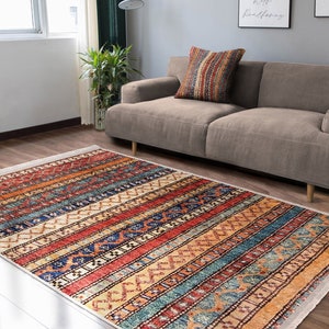 Hereke Motif Rug-A colorful, striped rug with a geometric pattern in shades of red, orange, blue, and yellow. The rug has a fringe border.