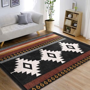 May include: Black and white geometric rug with red and orange stripes. The rug has a southwestern design with diamond shapes and a fringed edge.
