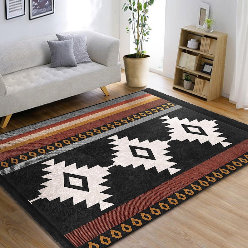 May include: Black and white geometric rug with red and orange stripes. The rug has a southwestern design with diamond shapes and a fringed edge.