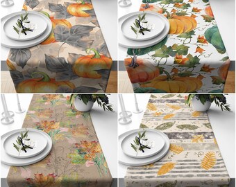Pode incluir: Quatro designs diferentes de caminhos de mesa com padrões de outono. Os designs incluem abóboras, folhas e um padrão listrado cinza e branco. Os caminhos de mesa têm todos 35,5 cm de largura e 177,8 cm de comprimento.