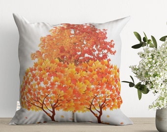 Può includere: Un cuscino bianco con un design autunnale colorato. Il cuscino presenta tre alberi con foglie arancioni, gialle e rosse.