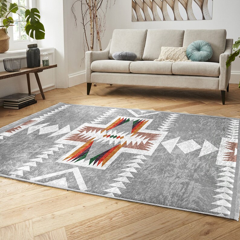 May include: A gray area rug with a white geometric pattern and colorful accents. The rug has a distressed look and is perfect for a living room or bedroom.