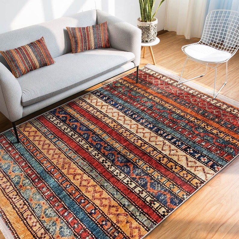 Hereke Motif Rug-A colorful, striped rug with a geometric pattern in shades of red, orange, blue, and yellow. The rug has a fringe border.